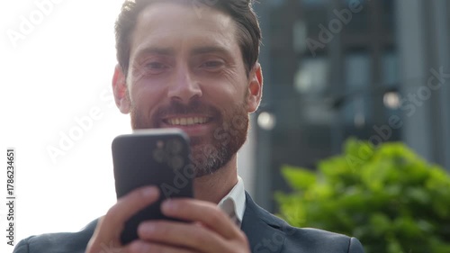 Business portrait happy mature man businessman looking in mobile phone smiling happy in city male executive entrepreneur reading good news email in smartphone scrolling app making order in downtown