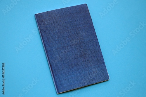 Generic passport book on light blue paper background close up. Travel document on blue surface