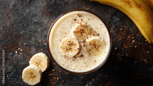 Creamy Banana Smoothie in Glass with Slices and Nuts on Table