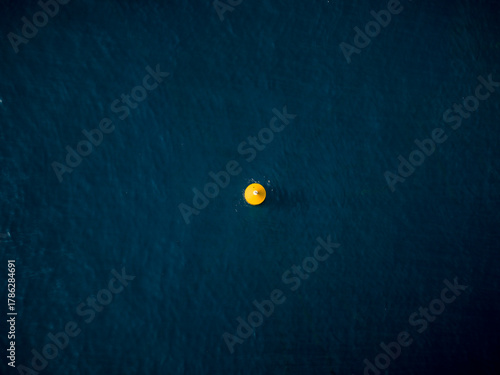 Aerial view of a vibrant yellow object contrasts against the deep blue sea, creating a striking visual focal point, Ksamil, Vlore County, Albania.