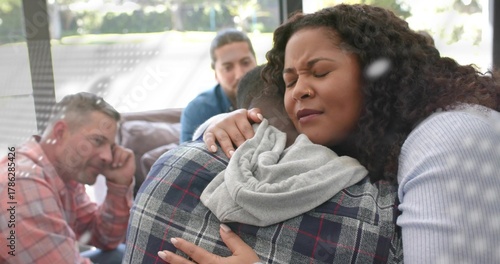 Hugging Mid adult African American woman consoling man in living room, with plaid shirt and hoodie