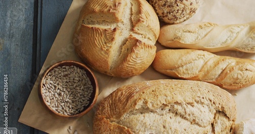 Displaying round boule, baguette, seeded roll on painted blue table with wooden bowl of seeds