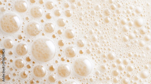 Close-up of frothy beer bubbles creating a textured surface, with soft lighting enhancing the creamy foam