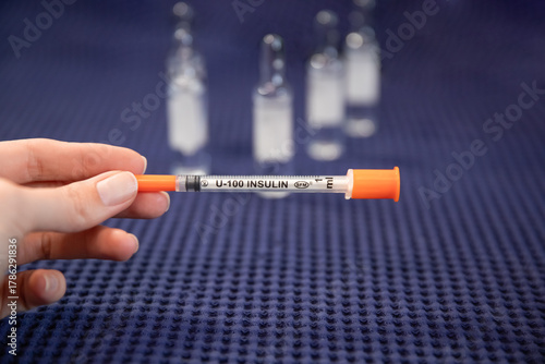 Woman holds insulin syringe medical background blurred