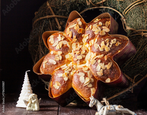 A star or snowflake shaped cupcake decorated with almond flakes, a wreath and Christmas tree decorations.
