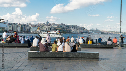 Konstfotografi Tourists sit on benches along the waterfront in Istanbul, Turkey, admiring the view of the waterfront with boats and the horizon
