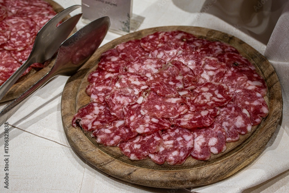 Obraz premium Sliced salami on wooden plate