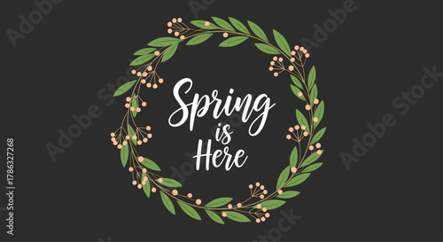 The words 'Spring is Here' are elegantly inscribed within a beautiful wreath of green leaves and delicate pink blossoms, celebrating the arrival of the spring season.