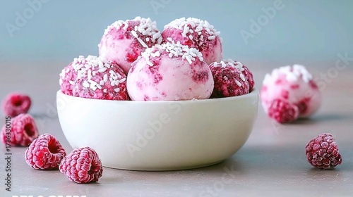 A white bowl filled with raspberry truffles covered in shredded coconut