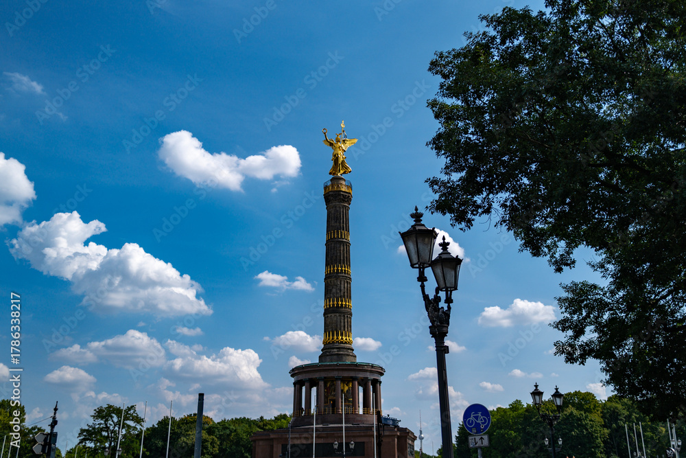 Obraz premium Historic monument under bright sky. Golden statue Victory Column above Berlin. Tourists visit iconic Victory Column. Architectural details in Berlin.