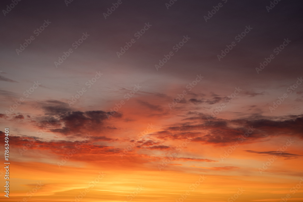 Fototapeta premium Vibrant sky displaying a stunning gradient of reds, oranges, and yellows with dramatic clouds during a colorful sunset, illustrating natural beauty and twilight atmosphere