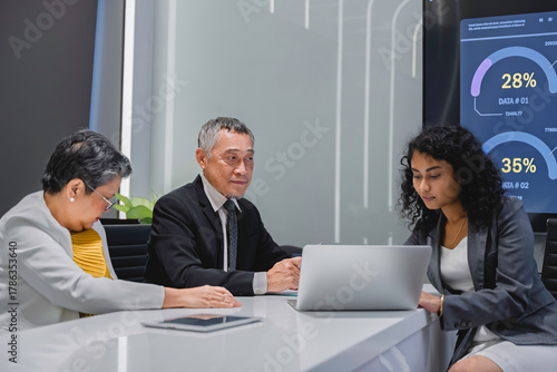 Diverse business team analyzing financial data and performance metrics during a corporate meeting. Professional teamwork, strategy planning, and data-driven decision making in modern office.