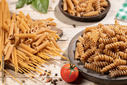 Variety of whole wheat pasta close up in rustic wooden kitchen.