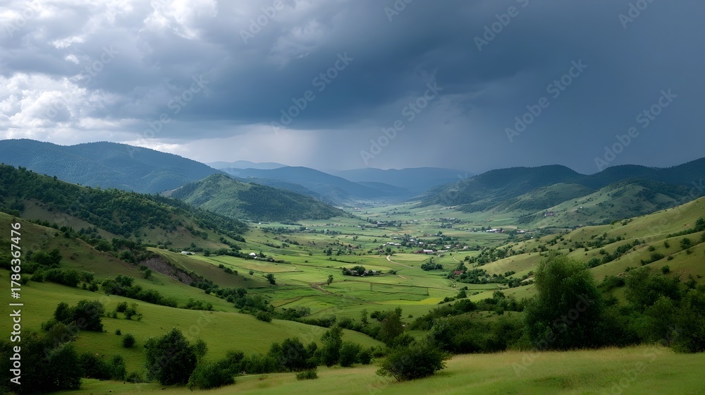 Obraz premium A dramatic stormy sky looms over a lush green valley with rolling hills and scattered rural settlements