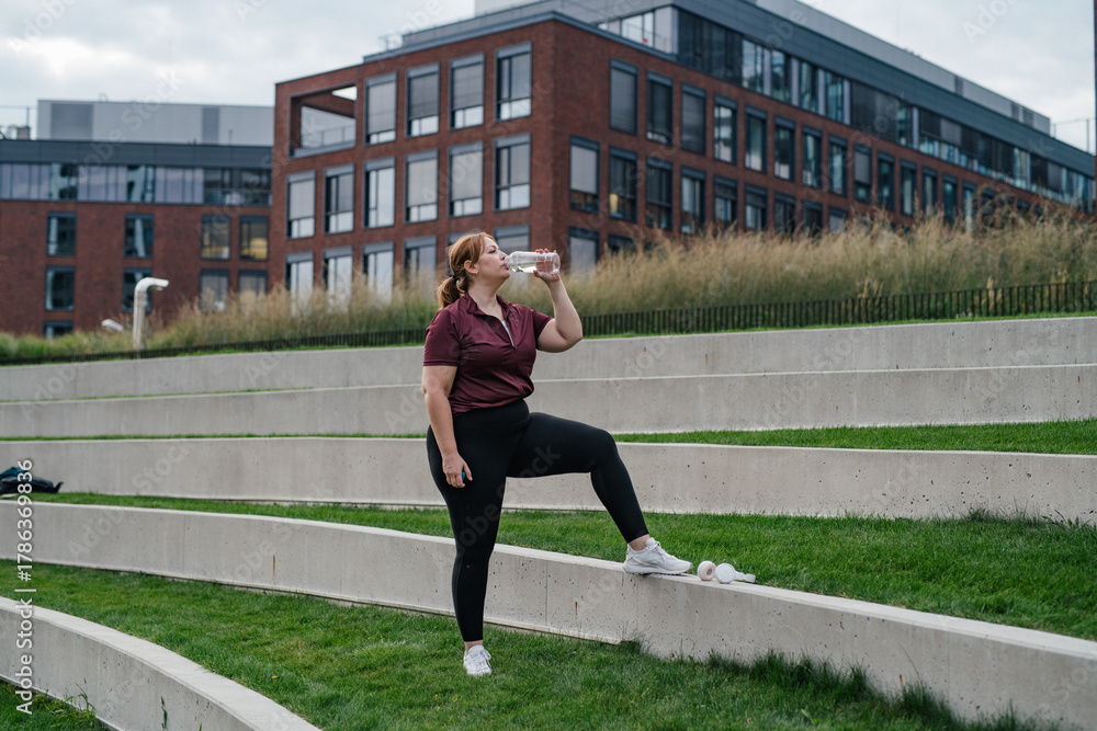 Fototapeta premium Sporty woman resting, drinking water after training.