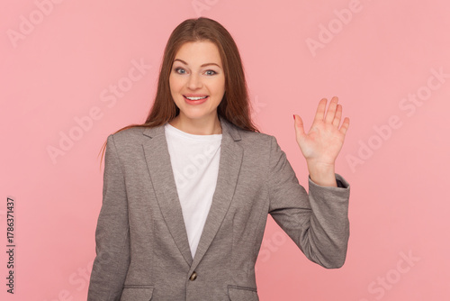 Friendly smiling woman waving hand, saying hello or good bye, expressing positive emotions
