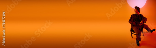 Stylish young man sitting on a chair against a vibrant sunset background