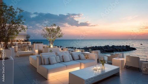 Scenic outdoor lounge area with ocean view at dusk under a colorful sky