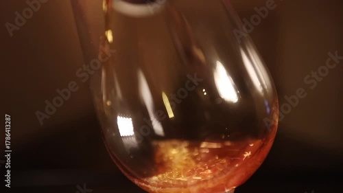 Dark craft lager beer being poured in beer glass, dark environment and light effect.