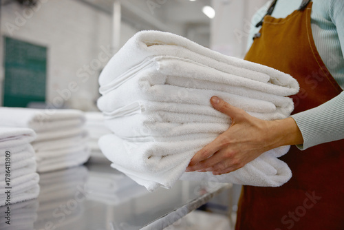 Closeup of a woman worker in an apron holds fresh towels in a laundromat
