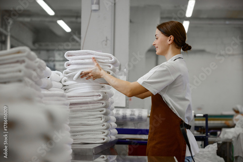 A woman worker is stacking towels neatly on a table in a laundromat