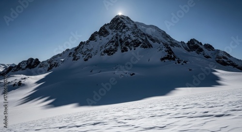 Majestic Snowy Mountain Peak Under a Bright Sun with Long Shadow.