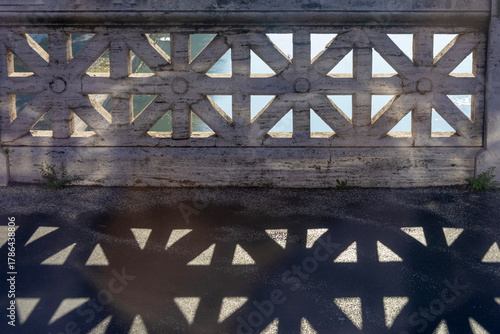 Geometry created by a balustrade against the sun and its shadow on the street, Rome, Italy