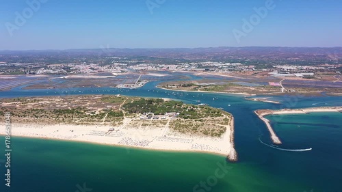 Aerial view drone shot of Tavira Portugal Algarve aerial view of channel entrance and coastal shoreline with boats navigating toward ria formosa local captain steering through clear green
