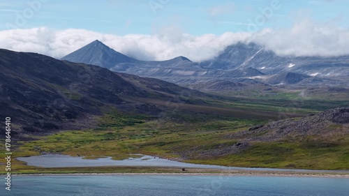 Wallpaper Mural Cinematic drone scene of Lavrentiya Bay where tundra meets a turquoise lagoon beneath rolling cloud. Ridges frame the coast as water shimmers in midday sun, inviting travel in remote Chukotka Torontodigital.ca