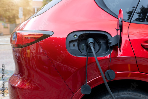 Close-up modern electric plug-in hybrid car SUV van parked   fast charger charging station point center street old European city. Eco friendly green energy vehicle. Zero emission transport technology