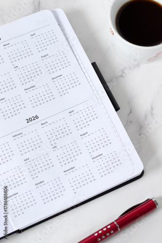 2026 calendar year in planner notebook with coffee cup and pen. Monthly budget, schedule, and annual business goals concept.