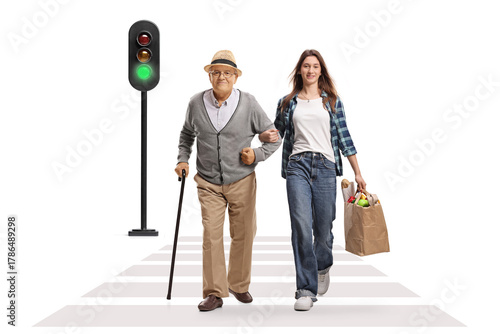 Young female carrying a grocery bag and walking with a senior man at zebra crossing
