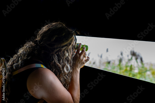 Canvas Print Young female tourist observes flowers, birds and bees with binoculars from an ob