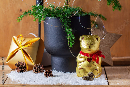 Christmas arrangement with an araucaria, a chocolate bear, gifts, a candle, and a star.