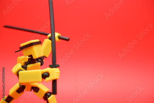 Toy Action Figure Posing with Dual Swords on Red Background
