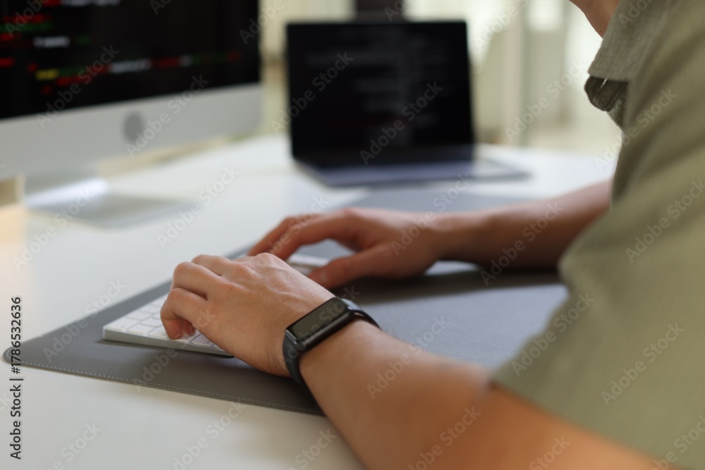 Fototapeta premium Programmer typing on keyboard at white table indoors, closeup