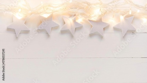 Video of flickering christmas star garland on white wood background