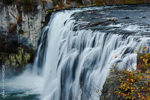 A powerful waterfall crashes over basalt cliffs, filling the canyon with swirling mist.