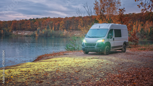 panoramic view in twilight to white camper van on lake coast in rainy evening with copy space