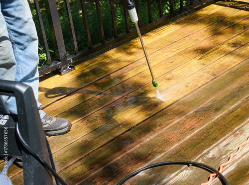Using a pressure washer to clean the old finish off of a wooden deck
