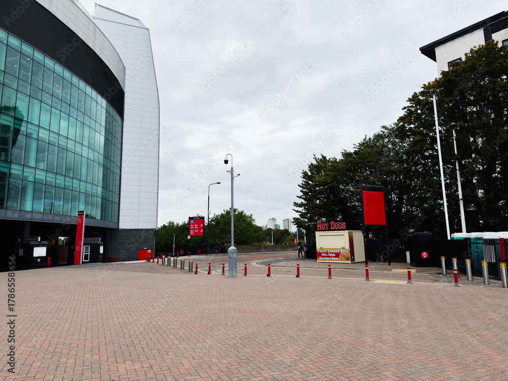 Fototapeta premium Manchester city center modern building with glass facade, plaza, red signage and street bollards