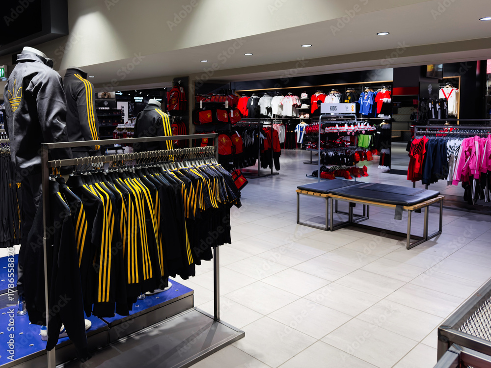 Fototapeta premium Modern Manchester store interior with sportswear on racks and a bench for shoppers