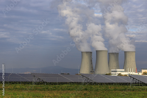Two energy sources together: solar panels and a nuclear power plant