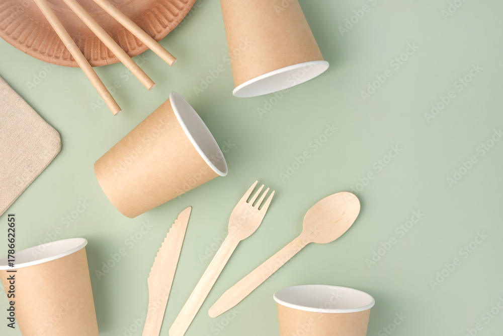 Fototapeta premium Eco - Friendly Tableware on Green Background. Top View. Plastic free Set of Brown Paper Utensil. Street Food Recyclable Packaging. Zero waste Paperware. Mockup. Disposable Take out Cup, wooden cutlery