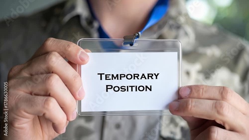Mans temporary position badge, reflection of job uncertainty driven by labor market shortage, points to contractual employment as modern stopgap solution