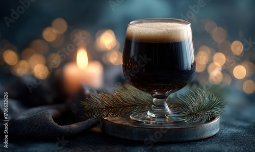 A glass of dark beer is sitting on a table next to a candle
