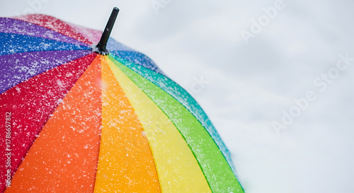 Colorful rainbow umbrella covered in snow during a winter day