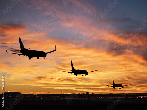 Silhouetted airliners landing at Seville Airport during sunset