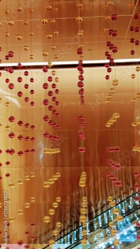 Golden Glow Reflections: Hanging Orbs in a Modern Mall Design
Golden and red glass orbs glow in symmetry above escalators, casting warm reflections across the modern shopping mall interior.
