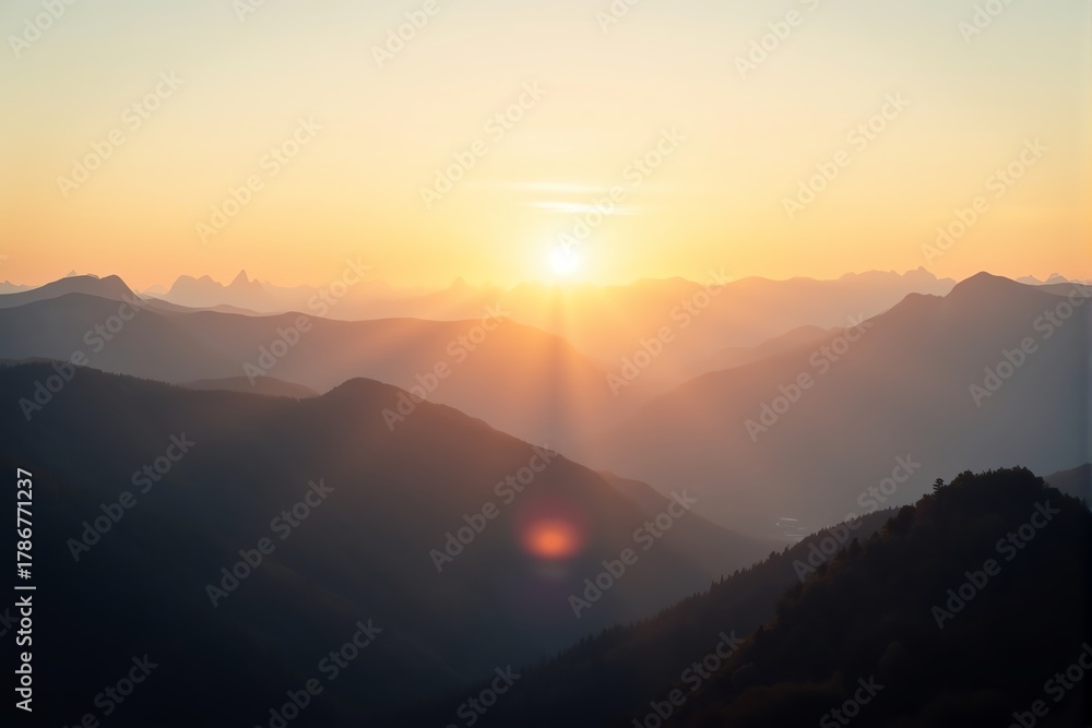 Obraz premium Golden sunbeams illuminate misty mountain peaks at dawn.